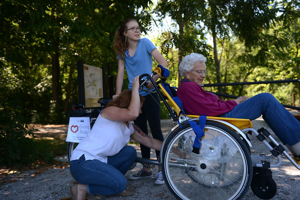 Heather Marriott adjusts the Duet tandem wheelchair bicycle while Veronica Fritz holds onto it